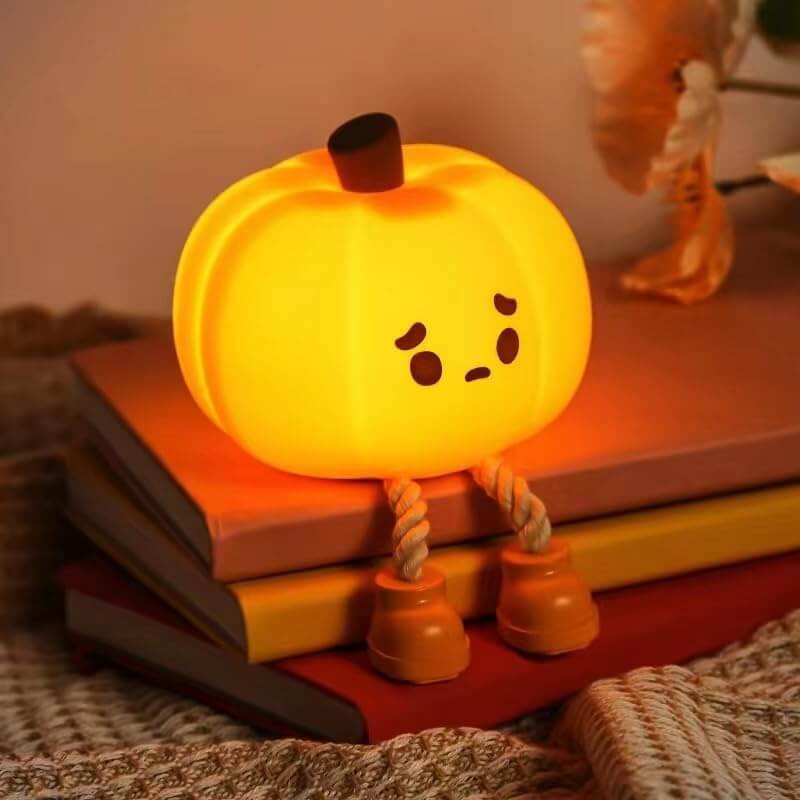 Cute pumpkin nightlight with a sad face sitting on books, creating a cozy and warm ambiance for autumn-themed decor.